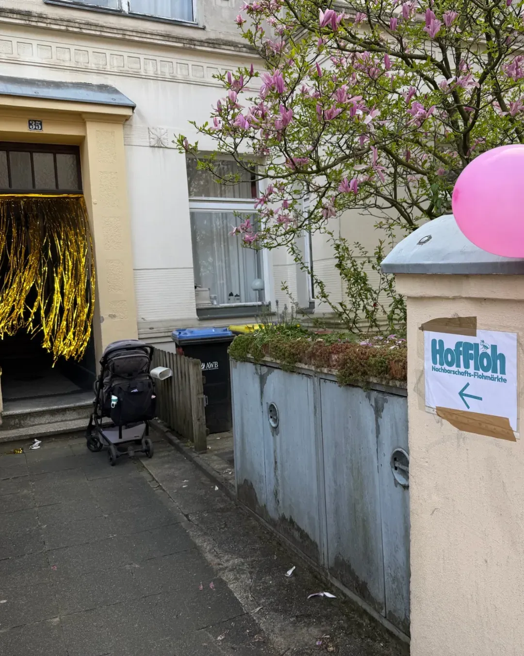 Hauseingang mit goldenem Lamettavorhang, rosa Luftballon und HofFloh-Wegweiser mit Pfeil