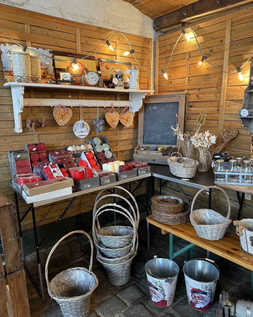 Stand in einem Holzverschlag mit Kerzen, Körben, Deko und Lichterkette