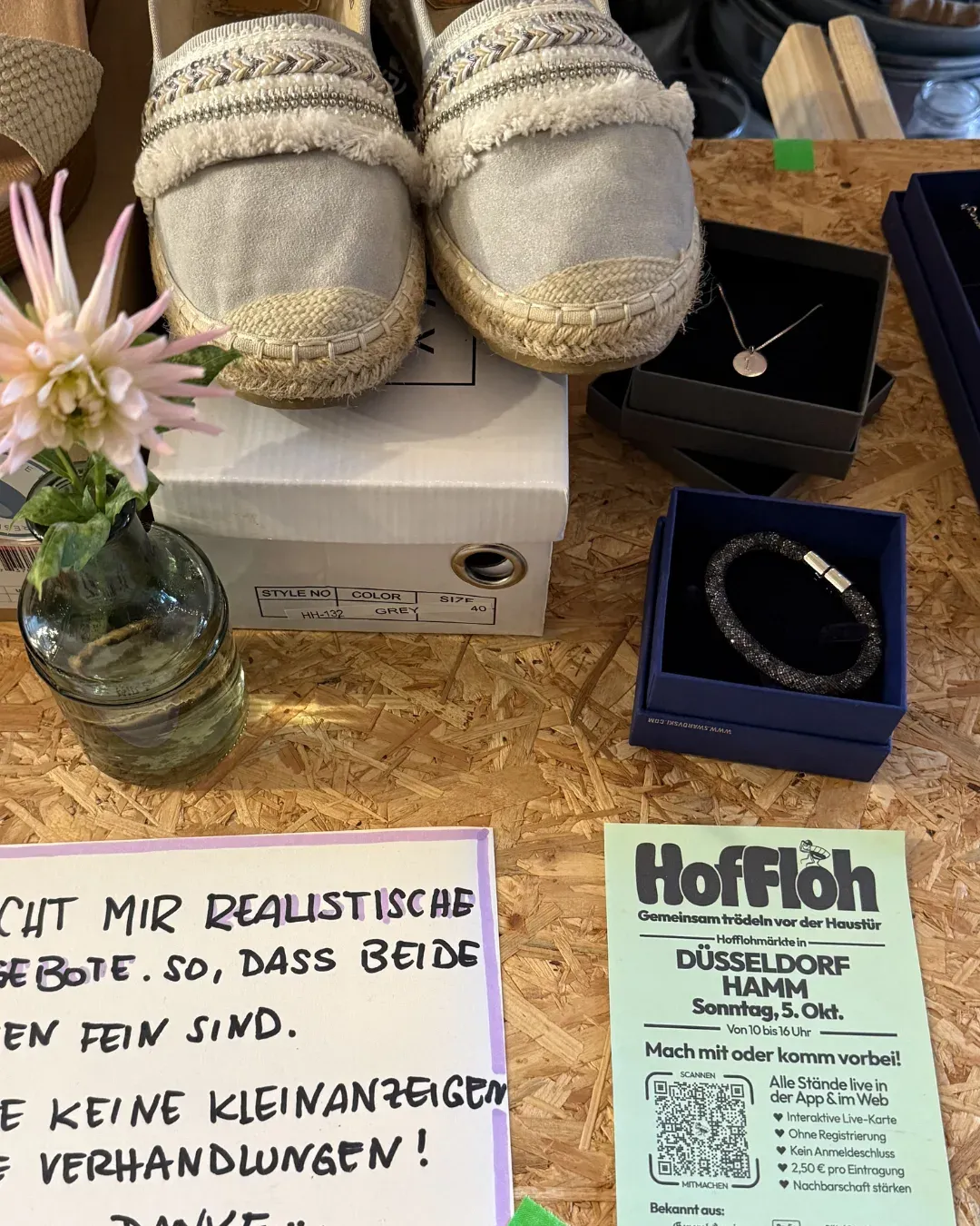 Espadrilles, Schmuck in Schachteln, ein Verhandlungsschild und ein HofFloh-Flyer auf einem Tisch