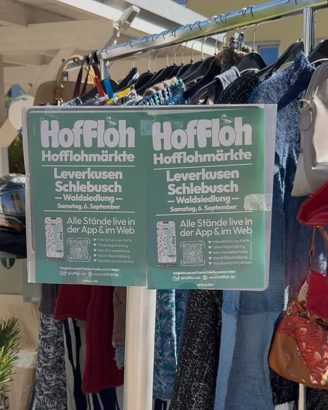 HofFloh-Plakate „Leverkusen Schlebusch Waldsiedlung, Samstag, 6. September“ an einer Kleiderstange
