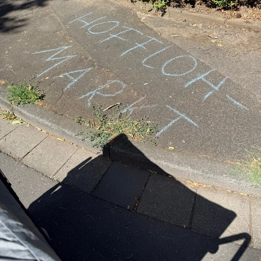 Kreideschrift „Hofflohmarkt“ auf dem Asphalt einer Straße